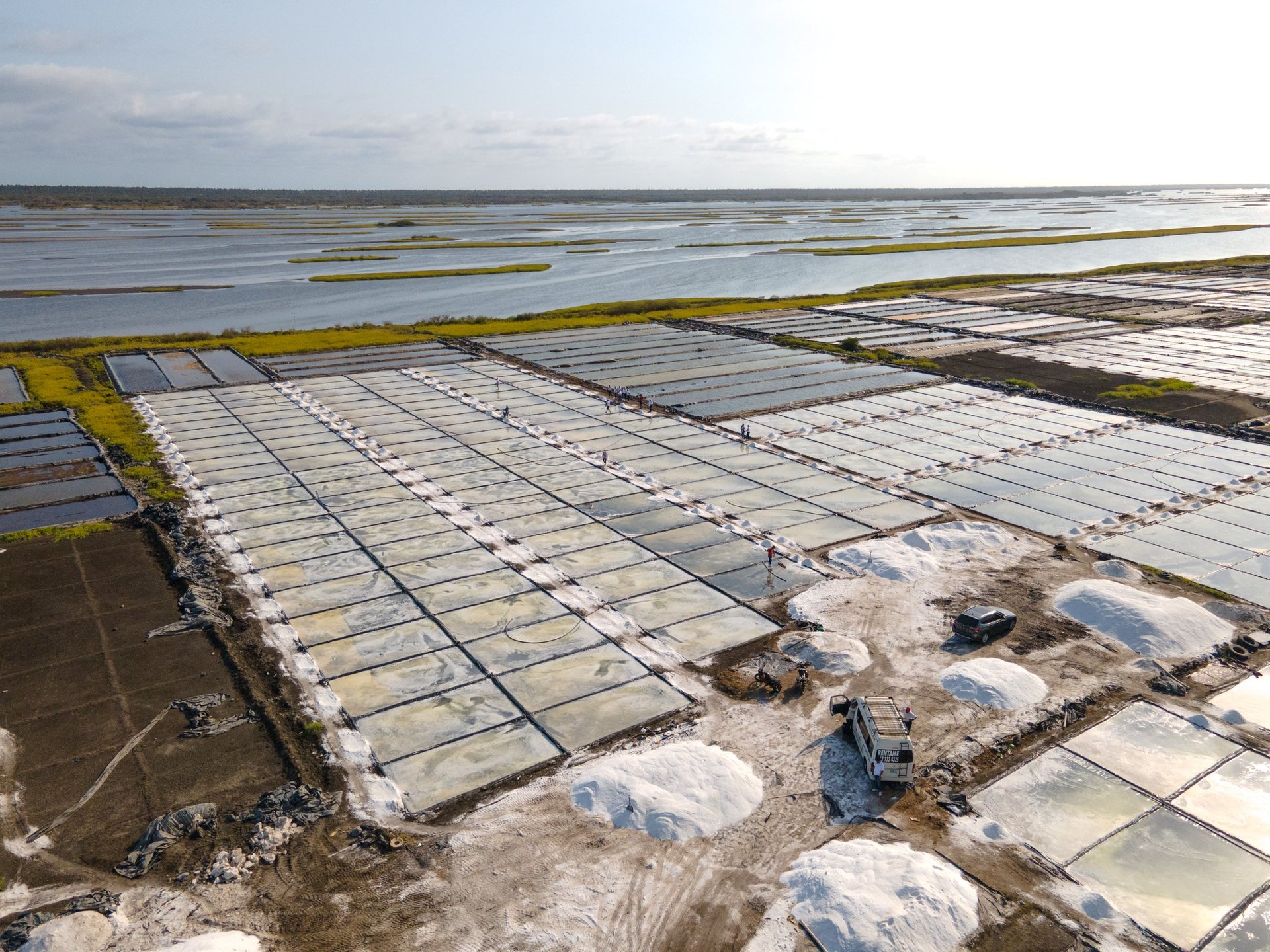 Aerial view of extensive salt evaporation ponds with geometric white rectangular sections divided by embankments and waterways